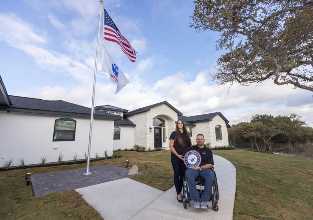 Veteran family outside their home with a plaque from the Gary Sinise Foundation. 